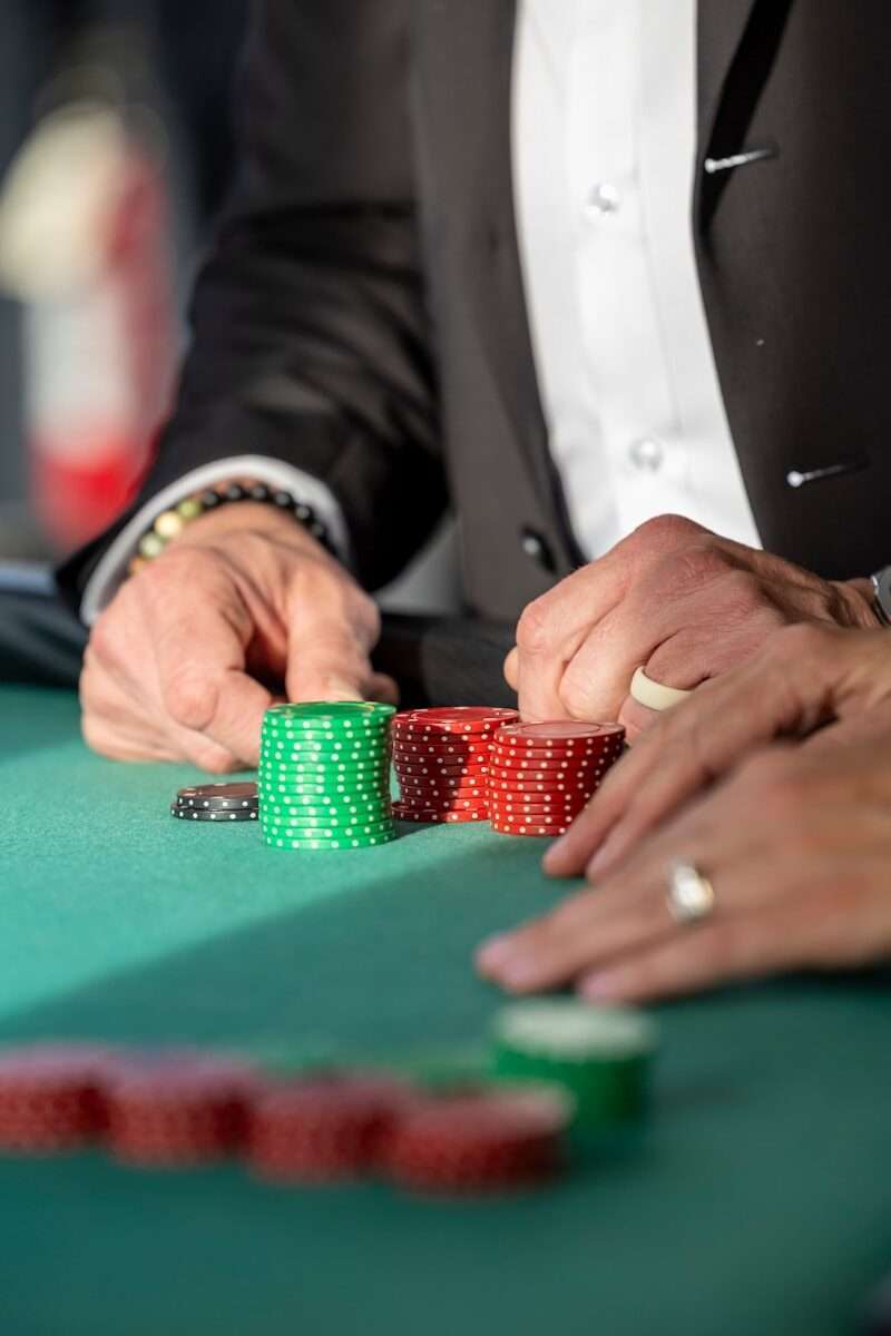 Hands reaching for poker chips on a green table